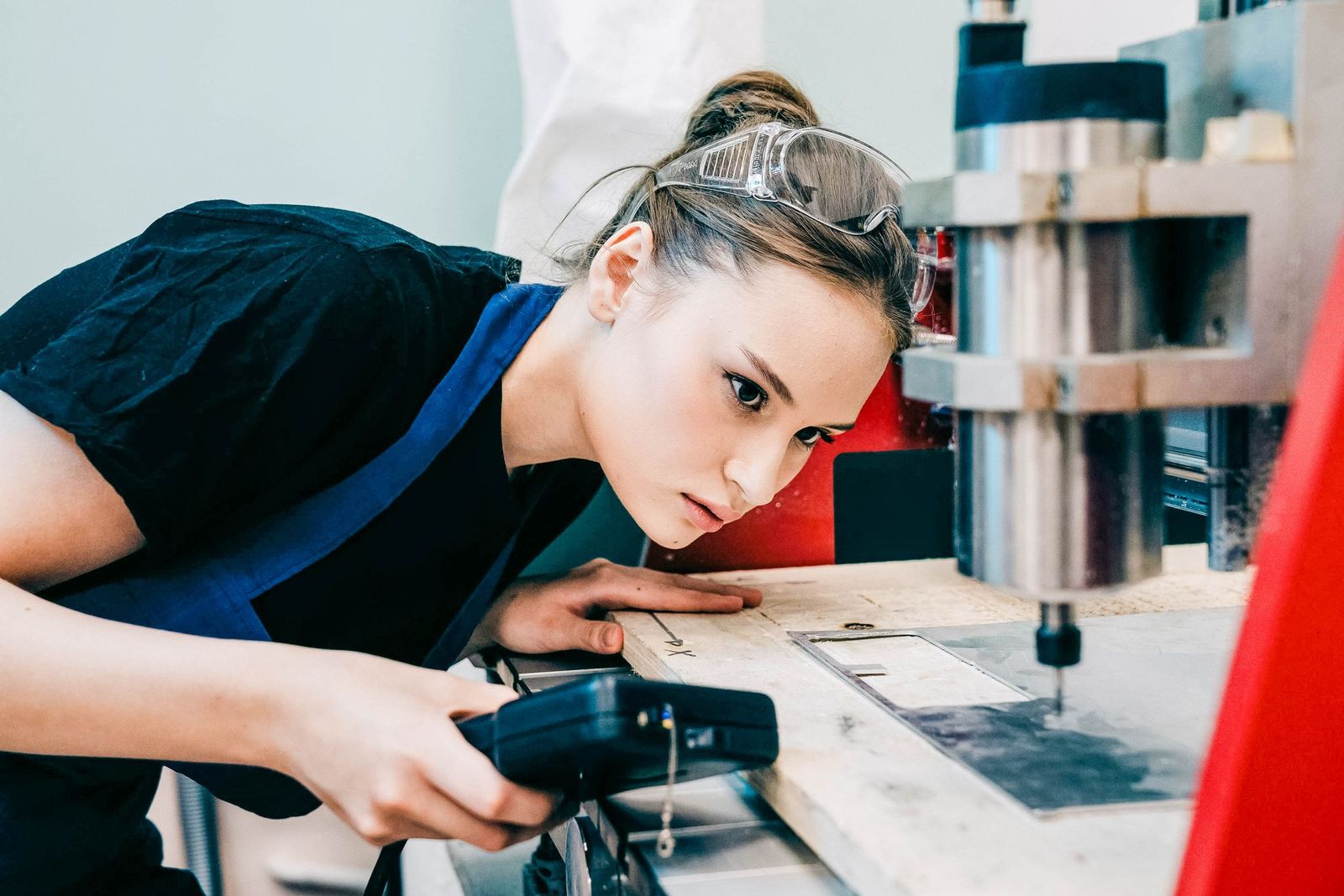 Junge Auszubildende bedient konzentriert eine Maschine
